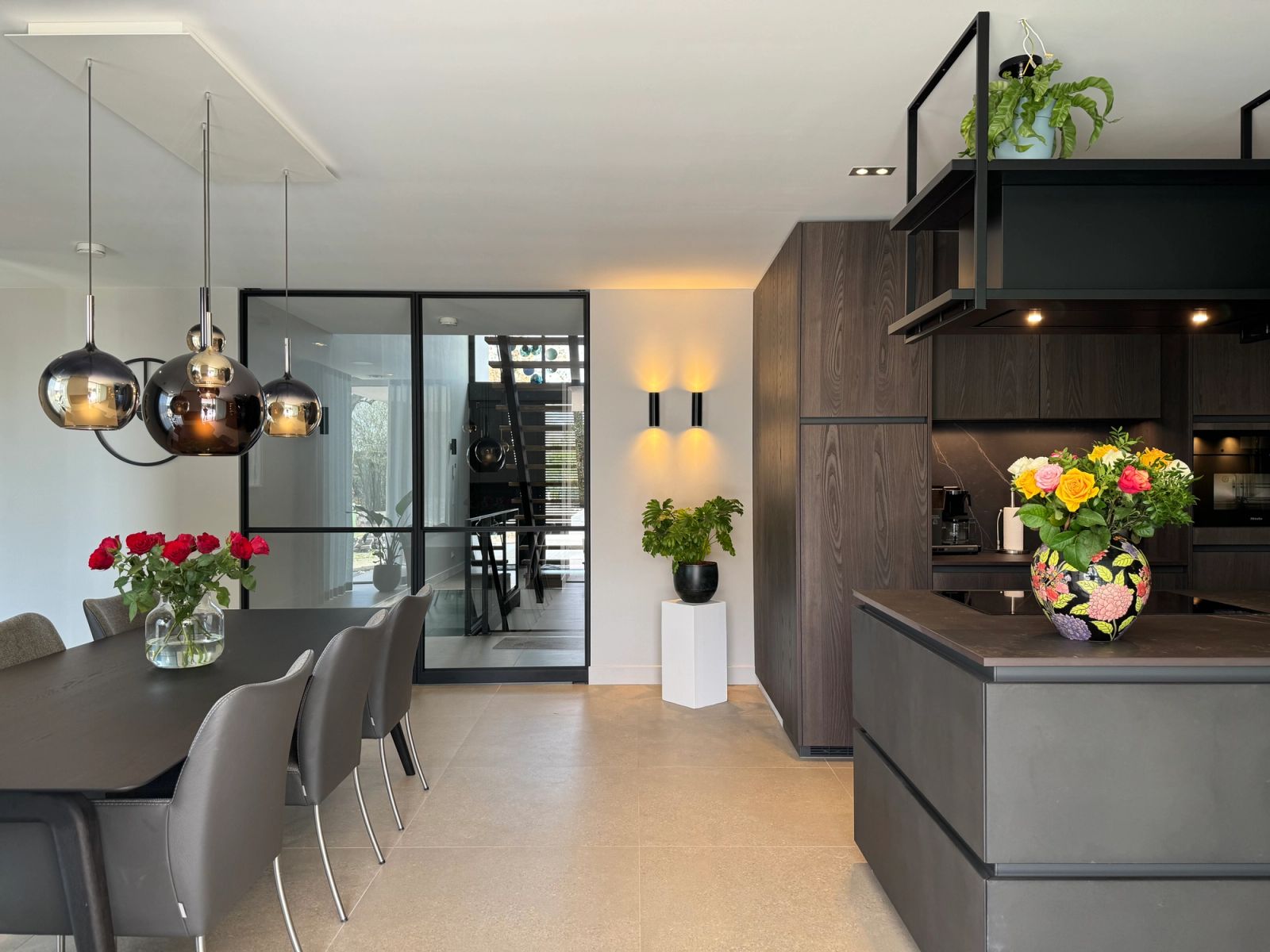 Zicht vanuit de eetkamer op het betonnen kookeiland en de iepenhouten kastenwand