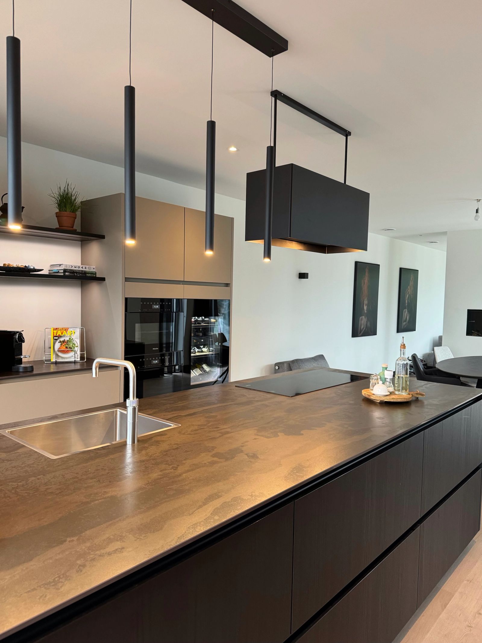 Werkblad met spoelbak en zwarte hanglampen in een keuken in zwart eiken en taupe