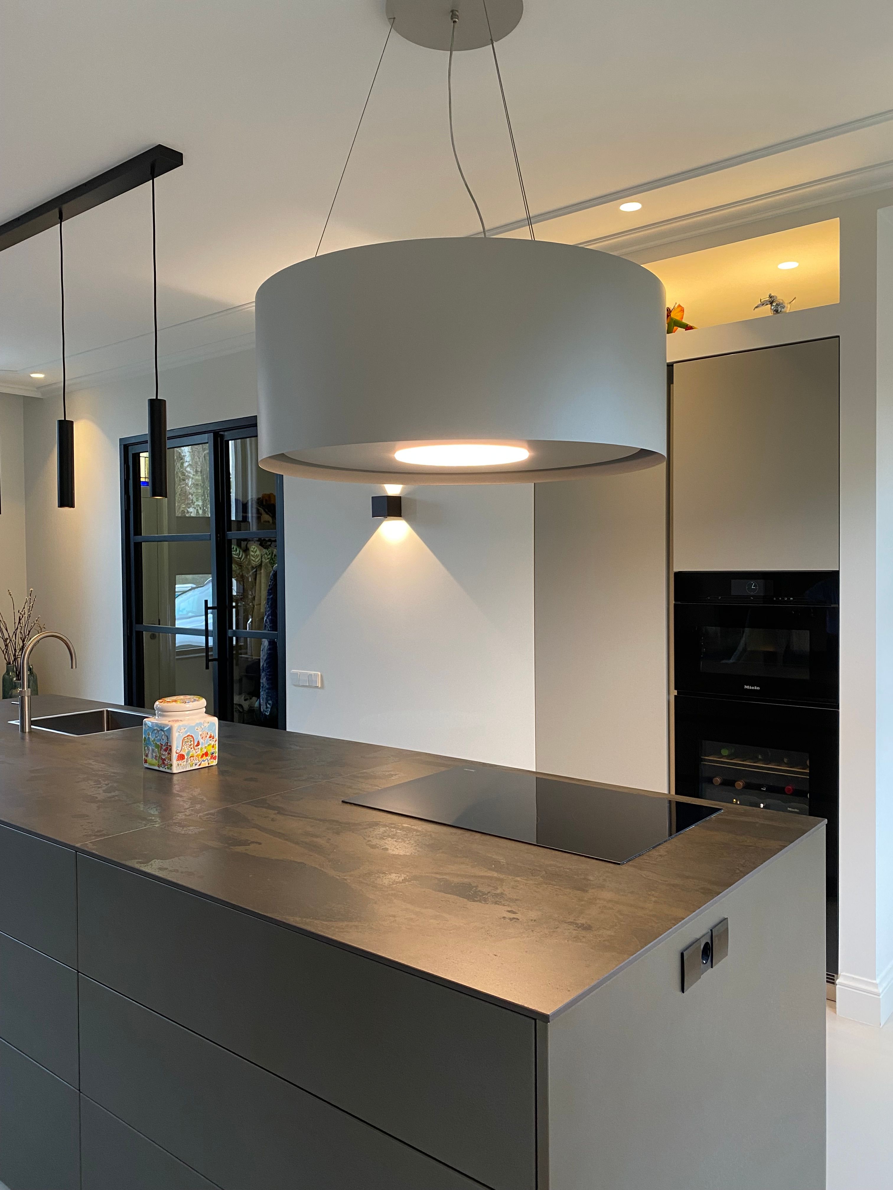 Olijfgrijze hoge kasten met Miele ovens naast het eiland