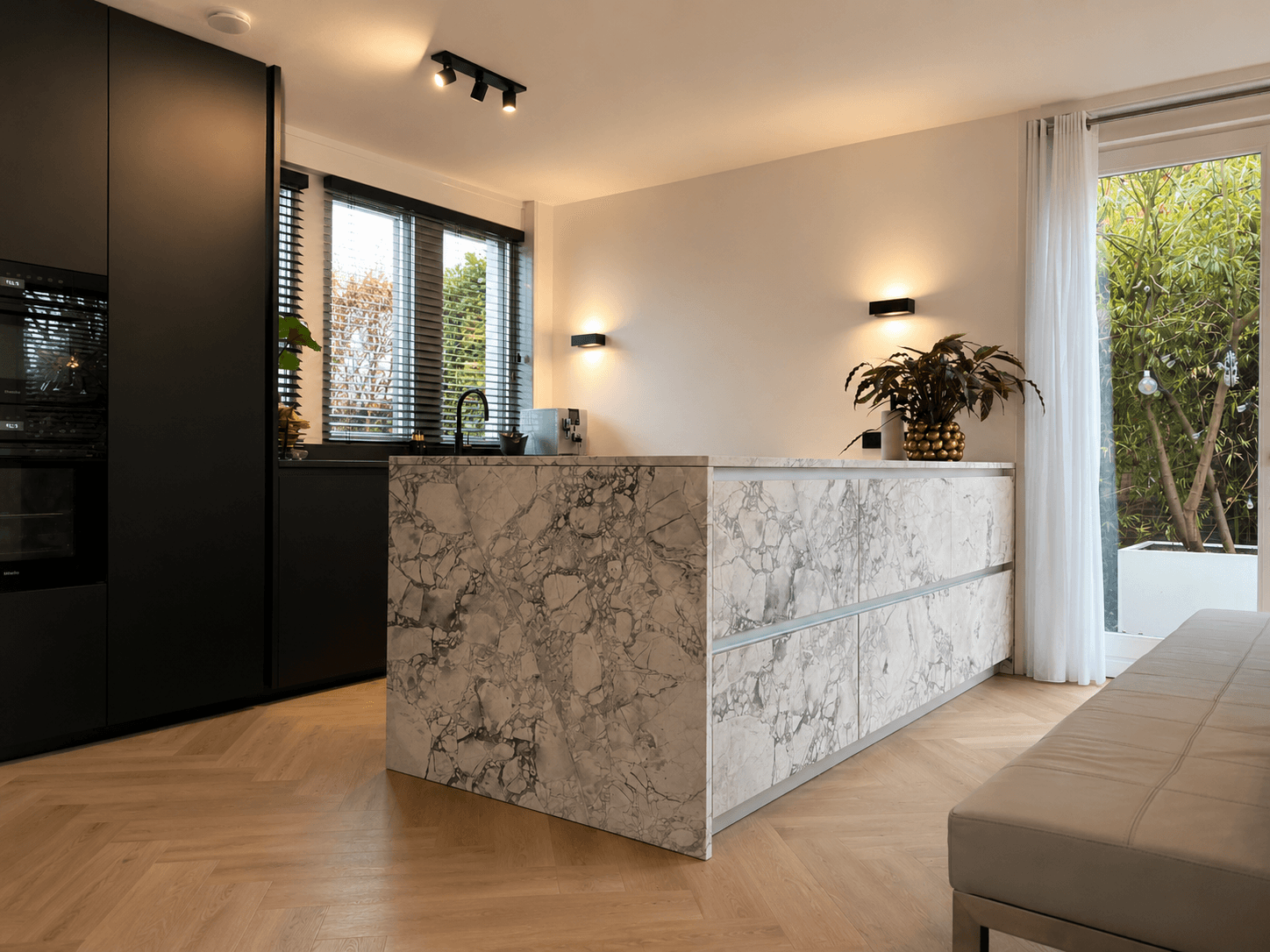 Maatwerk designkeuken met zwarte Fenix-fronten en een marmeren eiland van natuursteen, geleverd door Wildhagen