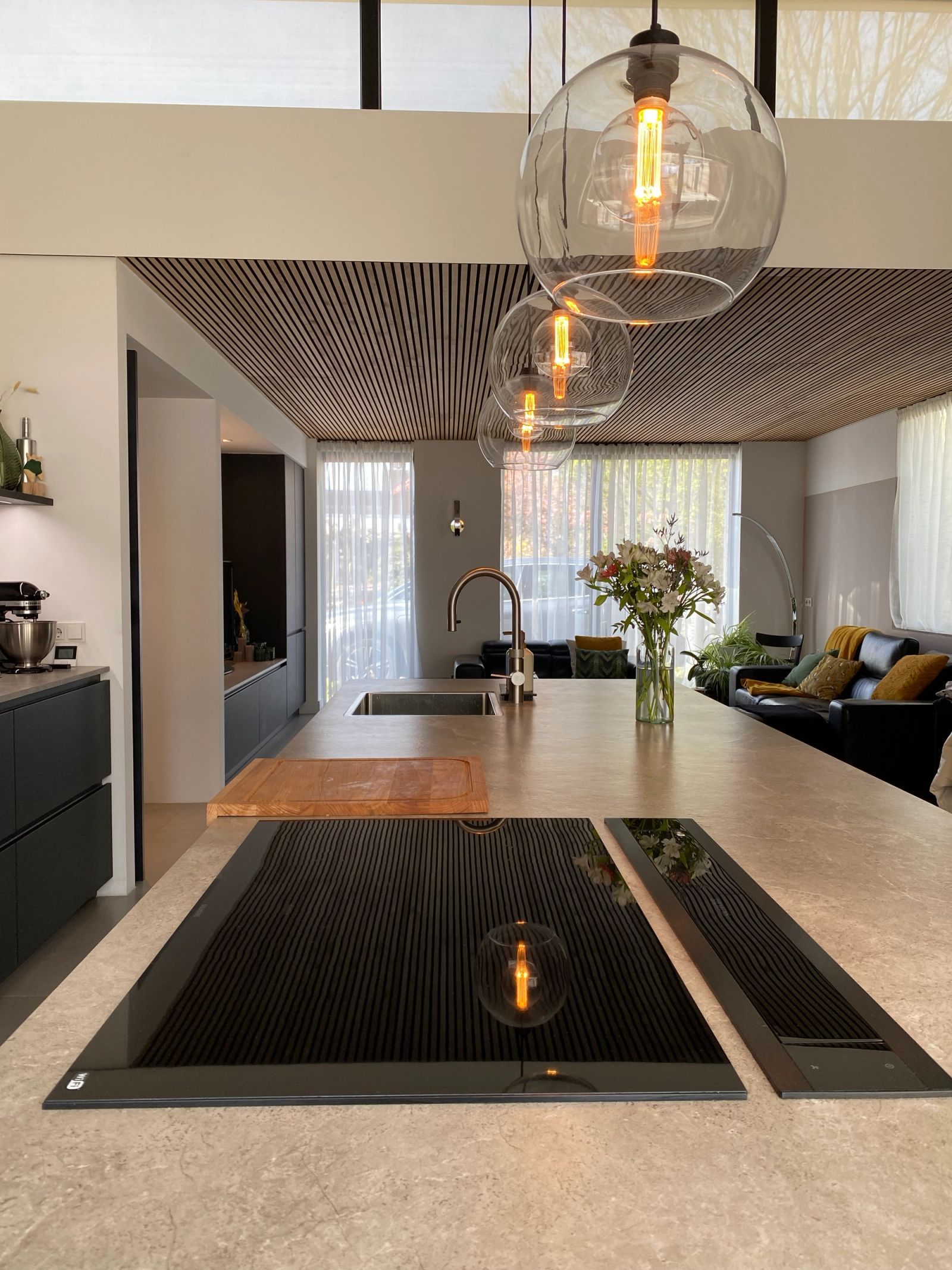 Kookeiland met inductie en downdraft-afzuiging onder de glazen bollampen